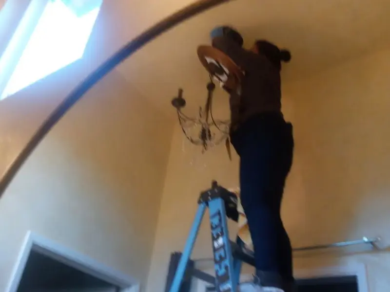 Electrician installing a chandelier in a Keyser residence